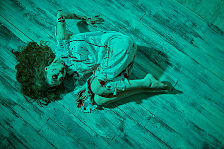 A terrible disfigured woman, possessed by the devil lies in a dark room covered in blood after the ritual of exorcism. Creepy zombie woman. Horror, thriller. Halloween.の写真素材