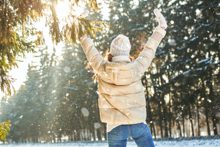 Portrait of a girl in fashionable winter clothes enjoying a snowy day in the park. Walk in a winter park on a sunny day. Winter activities.の写真素材