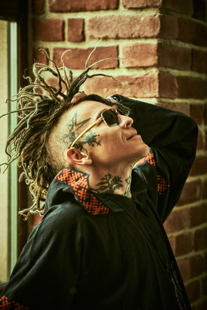 Profile portrait of a  mature brutal man with ethnic tattoos on his head and neck and with punk-style Mohawk dreadlocks. Punk and rock culture.の写真素材