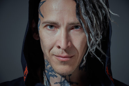 Punk and rock culture. A mature brutal man with ethnic tattoos and punk-style Mohawk dreadlocks...