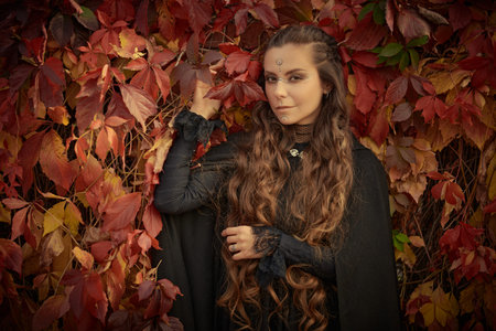 A beautiful shaman woman with long curly hair and ethnic ornaments on her face dressed in black...
