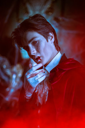 Vampires. A teenage vampire aristocrat stands in an abandoned medieval castle and wipes drops of blood from his lips after biting the victim. A novel about vampires. Halloween.の写真素材