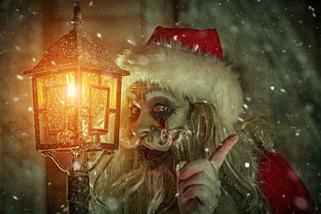 A portrait of a terrible zombie Santa Claus, who stands in the night at the lantern under the...