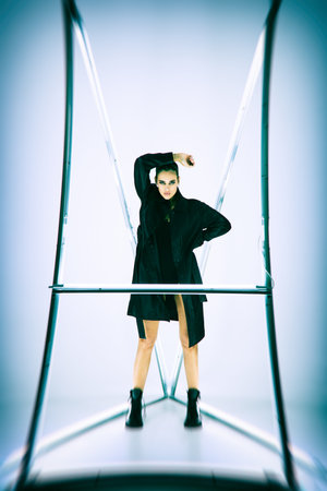Fashion portrait of a stunning sexual brunette girl model in a black bodysuit, black leather coat...