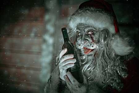 Christmas, New Year and Halloween. Merry and scary zombie Santa Claus with a bloody beard stands by his wooden hut with a bottle of alcohol and laughs wickedly. Copy space.の写真素材
