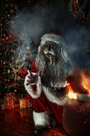 Christmas and Halloween. Scary Zombie Santa Claus is sitting by a Christmas tree, entangled in cobwebs, and is laughing evilly.の写真素材
