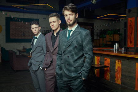 Men's fashion. Three handsome men in elegant suits standing together in a restaurant.の写真素材