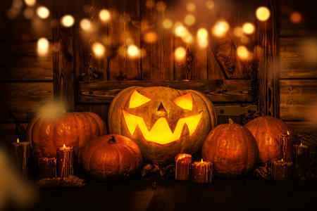 Sinister jack-o'-lantern pumpkin with a scary smile among pumpkins and candles surrounded by magic lights. Halloween scary tales.の写真素材