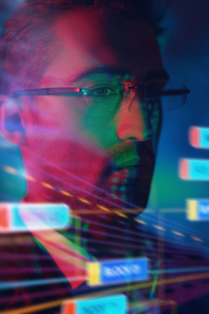 A close-up portrait of a serious man in glasses and suit standing in front of a digital hologram.