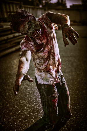 Zombie attacks. Angry bloody zombie man stretches its arms forward towards the victim standing in destroyed city. Halloween. Horror movie. Zombie apocalypse.の写真素材