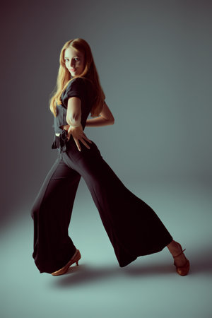 Portrait of a graceful beautiful girl dancing at studio in black top, pants and shoes. Beauty and Fashion. Modern ballet dances.の写真素材