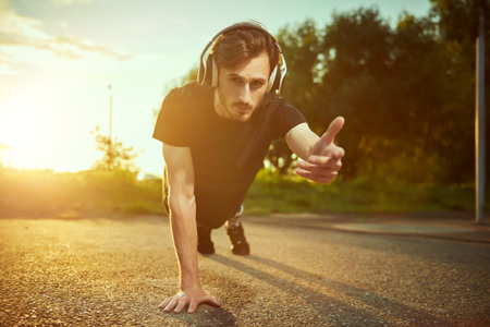An active young man is doing push-ups from the floor on the ground in the park. Sport and fitness....