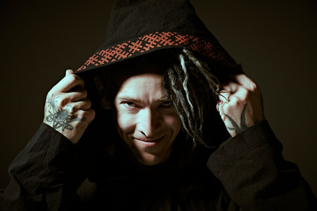 Portrait of a brutal mature man with ethnic tattoos and mohawk dreadlocks on his head posing expressively on a dark studio background. Rock musician. Ethnic rock and punk culture.の写真素材