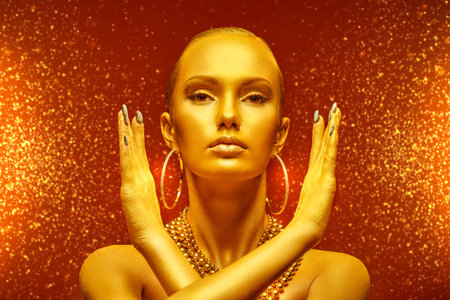Christmas beauty girl. Gorgeous young woman with golden skin, makeup and hair posing in golden...