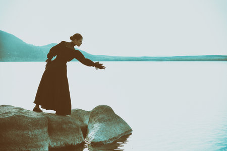 Beautiful vintage woman in elegant black dress is going to drown herself in the sea to get rid of her internal pain and sufferings. 19th century novel. Copy space.の写真素材