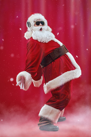 A full length shot of cool Santa Claus in sunglasses listening to music on headphones, singing and dancing. Merry Christmas. Party. Red background with snow.の写真素材