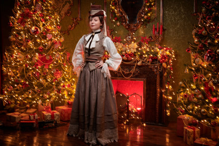Steampunk Christmas. Elegant confident steampunk lady stands in a vintage room fabulously and ornately decorated for Christmas. Style 19th - early 20th century.の写真素材