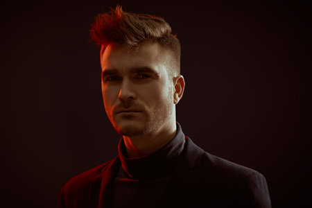 A handsome brutal man posing in the mixed light. Black studio background with copy space. Psychological art portrait.の写真素材