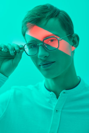 A studio shot of a handsome blond man in an elegant white shirt and stylish glasses. Successful...
