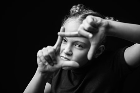Black and white portrait of a little girl making a frame with her fingersの写真素材