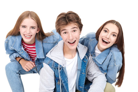 Fashion shot of two pretty teen girls and a handsome teen boy in trendy denim clothes posing on a white studio background. Denim fashion, teenage style. Education.の写真素材