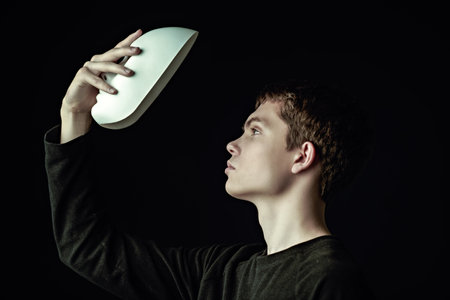 Roles of people. A handsome young man in a black pullover holds a white mask in his hand. Psychology, inner world.の写真素材