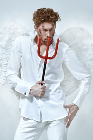 A sexy handsome man, Fallen Angel Lucifer with wounds on his face, holds a trident looking...