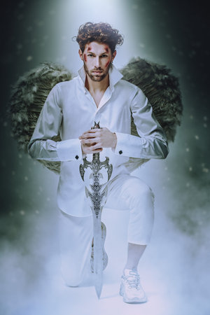 The majestic Archangel stands guard with a sword in his hands. Light falling from above. Fantasy...