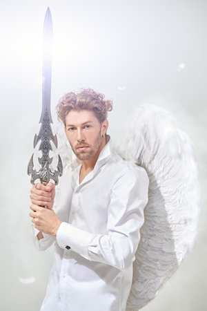 The majestic Archangel stands guard with a sword in his hands in front of him. White background with...