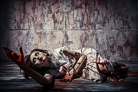A terrible disfigured woman, possessed by the devil lies in a dark room covered in blood after the ritual of exorcism. Creepy zombie woman. Horror, thriller. Halloween.の写真素材
