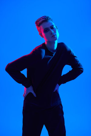 Art portrait of a sensual handsome young man posing at studio on a blue background in mixed colored...