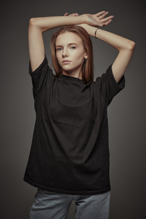 Young beautiful confident girl posing in a black t-shirt and jeans on a gray studio background. Young generation, active lifestyle.の写真素材