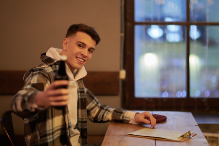 A modern young man hangs out in a bar drinking beer. Free time, lifestyle.