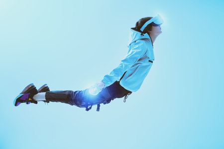 Virtual reality games. A modern teenage boy flies through the air wearing virtual reality glasses,...