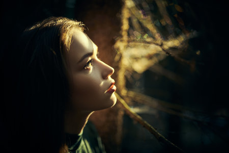 Sideview shot of a pretty girl in a green dress got lost in a dark fairy forest and looking up in search of salvation. Fairy tale heroine. Fantasy.の写真素材