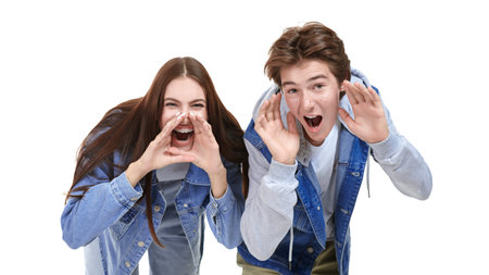 Portrait of an emotional teen boy and girl in trendy denim clothes shouting to the camera. White...