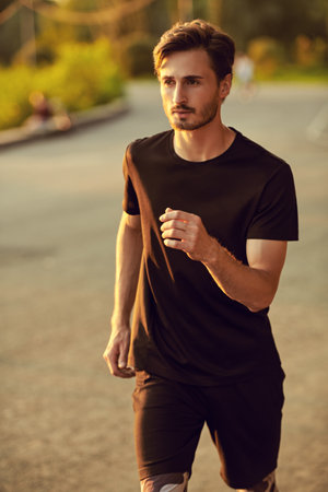 Sport is life. A handsome athletic brunet man goes jogging at sunset. Sport and active lifestyle. Healthy life.の写真素材
