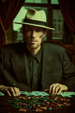 The criminal world of the mafia. A tough gangster man in an elegant black suit and a white hat sits...