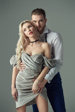 Portrait of a beautiful glamorous couple in elegant evening dresses. Evening Fashion. Studio portrait on a grey background with copy space.の写真素材