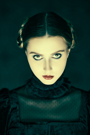 Portrait of a dramatic brunette girl in an elegant black velvet dress, who stands in the night on a dark vintage background. Gothic novel, mysticism. Makeup and hairstyle.の写真素材