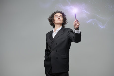 Inspired male conductor waves his conductor's baton. The magic of music. Inspiration. Studio portrait on a gray background.の写真素材
