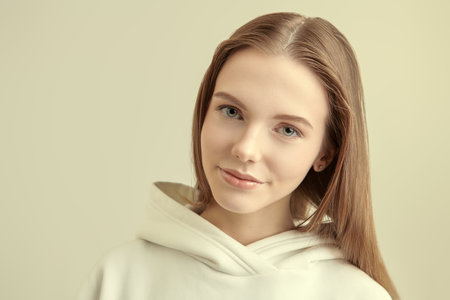 A cute girl teenager with long fair hair looking at camera and smiling. White studio background.の写真素材