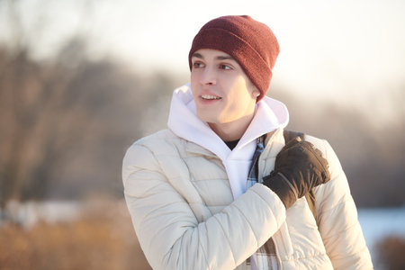 Happy people concept. Portrait of a handsome happy guy in winter clothes who is standing in the park and smiling broadly. Emotions. Copy space.の写真素材