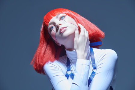 Cyberpunk concept. Portrait of a beautiful cyberpunk girl with bright red makeup and red hair posing...