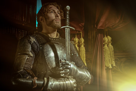 A scene from a chivalric romance. A handsome noble medieval knight in armor stands with his sword in...