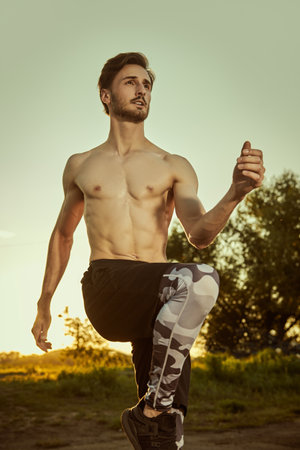 Sport is life. A handsome athletic brunet man goes jogging at sunset. Sport and active lifestyle. Healthy life.の写真素材
