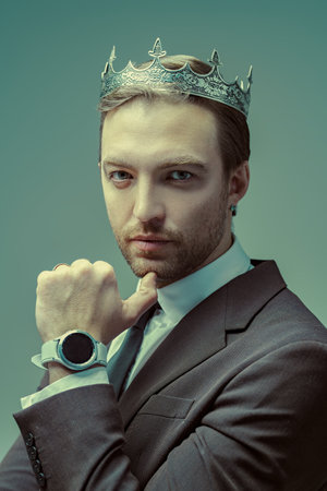 The concept of success. Portrait of a handsome well-groomed mature man dressed in a business suit and with a crown on his head, who looks calmly and confidently. Business and successful lifestyle.の写真素材