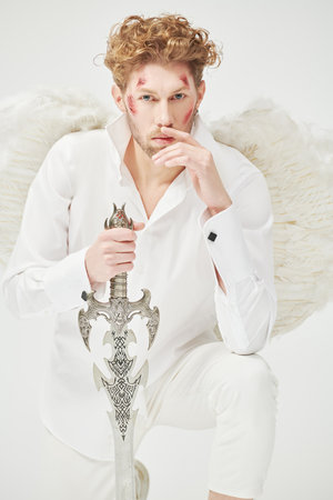 The majestic Archangel stands guard with a sword in his hands in front of him. White background. Fantasy hero. Valentine's Day.の写真素材