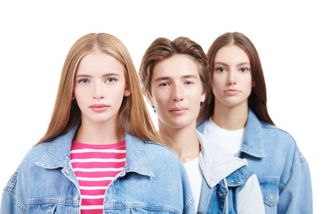 Denim fashion, teenage style. Fashion shot of two pretty teen girls and a handsome teen boy in trendy denim clothes posing on a white studio background. Education.の写真素材