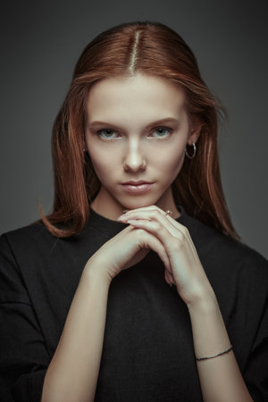 A tender girl teenager thinking about something. Dark gray studio background. Psychological art portrait.の写真素材
